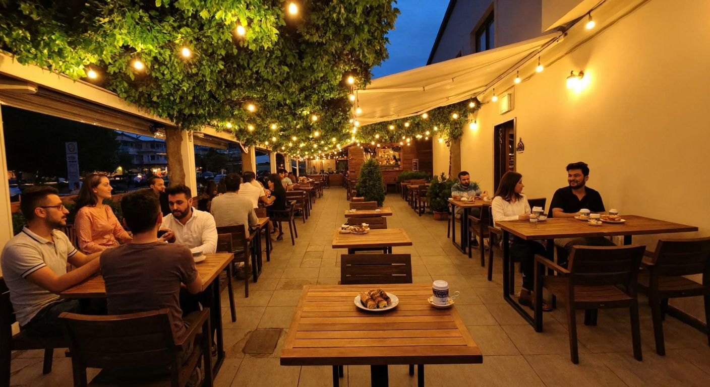 A cozy café terrace in Nilüfer, Bursa, with wooden tables under string lights, people chatting over Turkish coffee and baklava, surrounded by greenery and a warm evening glow.