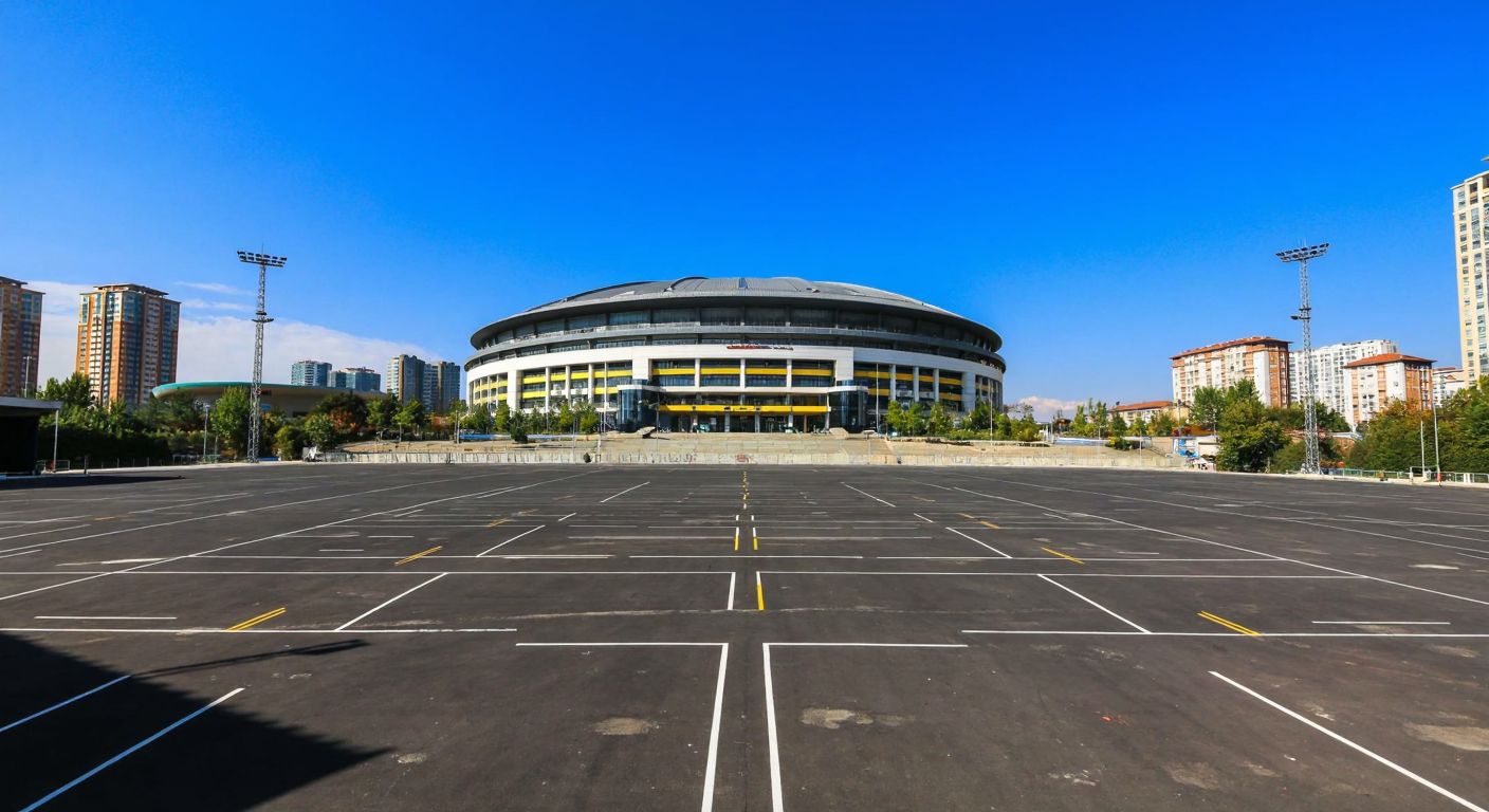 A vast, empty urban lot in Ataşehir with the Ülker Sports Arena in the background, under a bright blue sky, symbolizing Fenerbahçe's potential and unanswered financial details.
