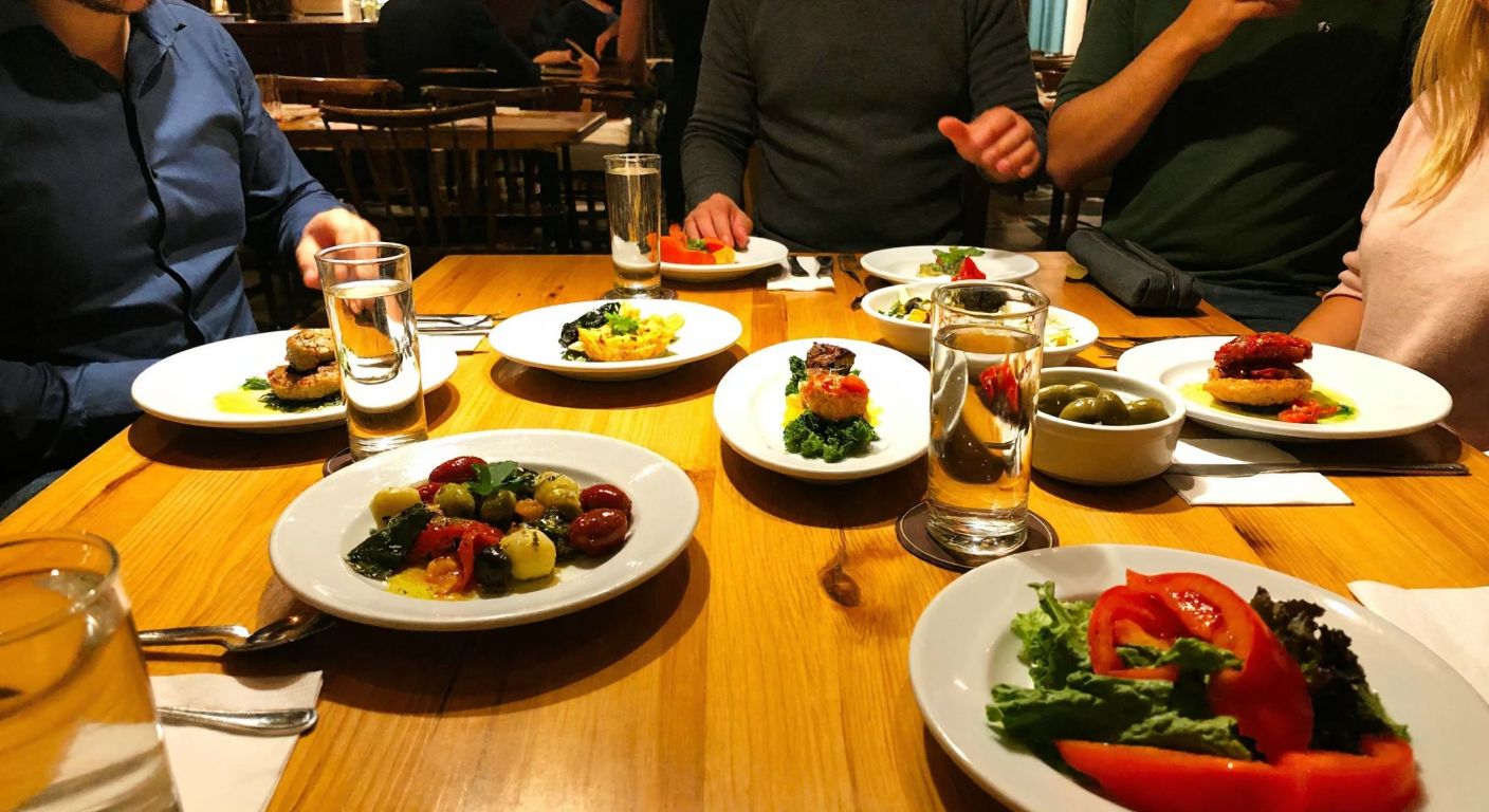 A cozy, warmly lit mezze restaurant in Kadıköy, Istanbul, with wooden tables adorned with small plates of colorful Turkish appetizers, glasses of raki, and a lively atmosphere of friends chatting.