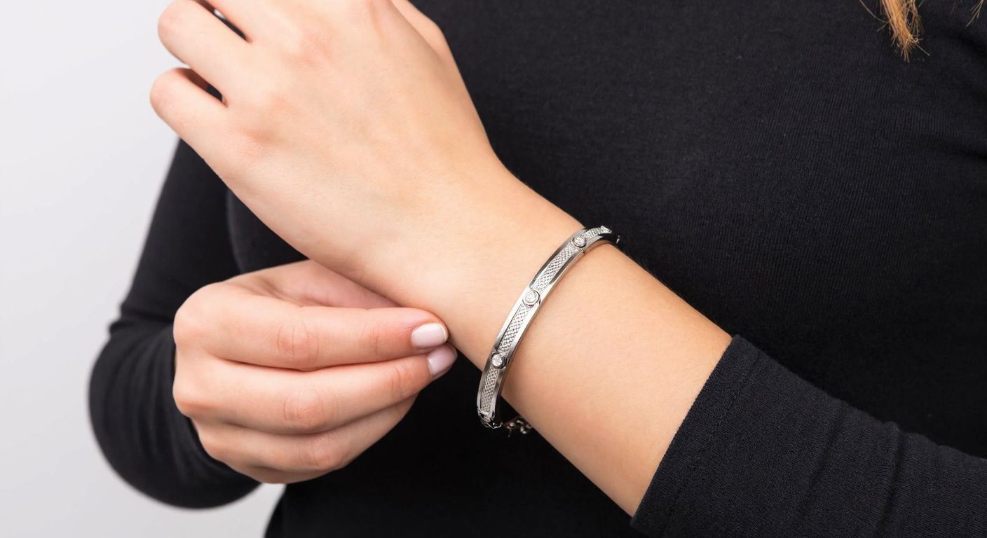A close-up of a Turkish woman’s slender wrist adorned with a gleaming steel bracelet, her fingers gently pressing the spring clasp to secure it in place.