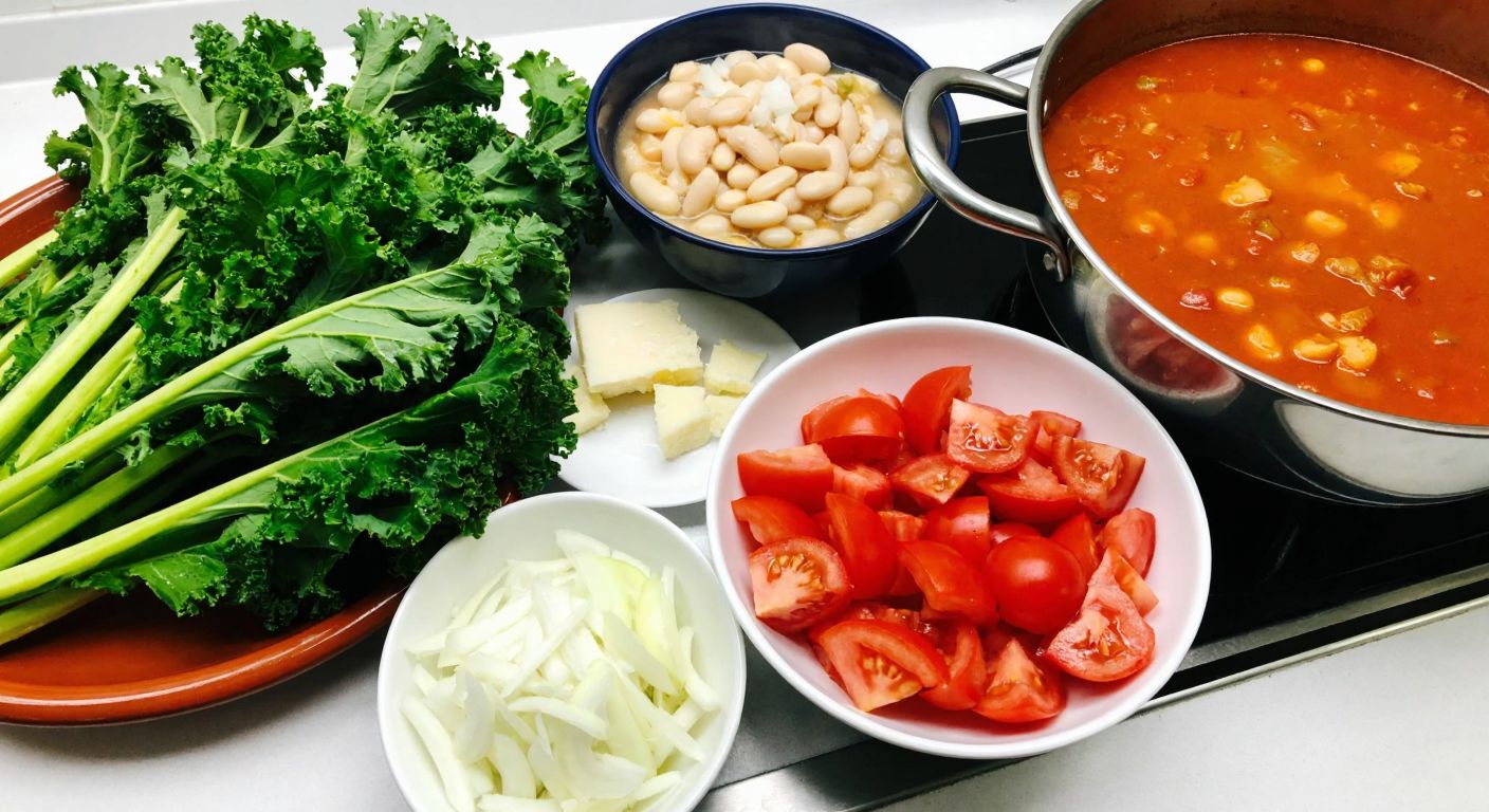 A vibrant Turkish kitchen counter displays fresh kale leaves, a bowl of chopped onions, anchovies, tomatoes, and parmesan cheese, with a steaming pot of white bean stew in the background.