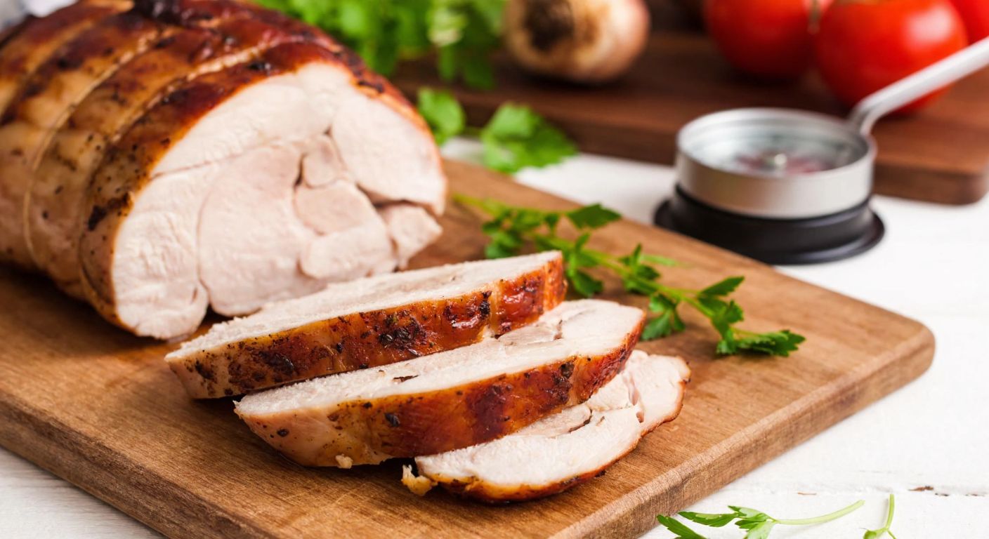 A close-up of a juicy, roasted turkey breast sliced on a wooden cutting board, with a small kitchen scale nearby and fresh herbs scattered around, evoking a warm, home-cooked meal in a Turkish kitchen.