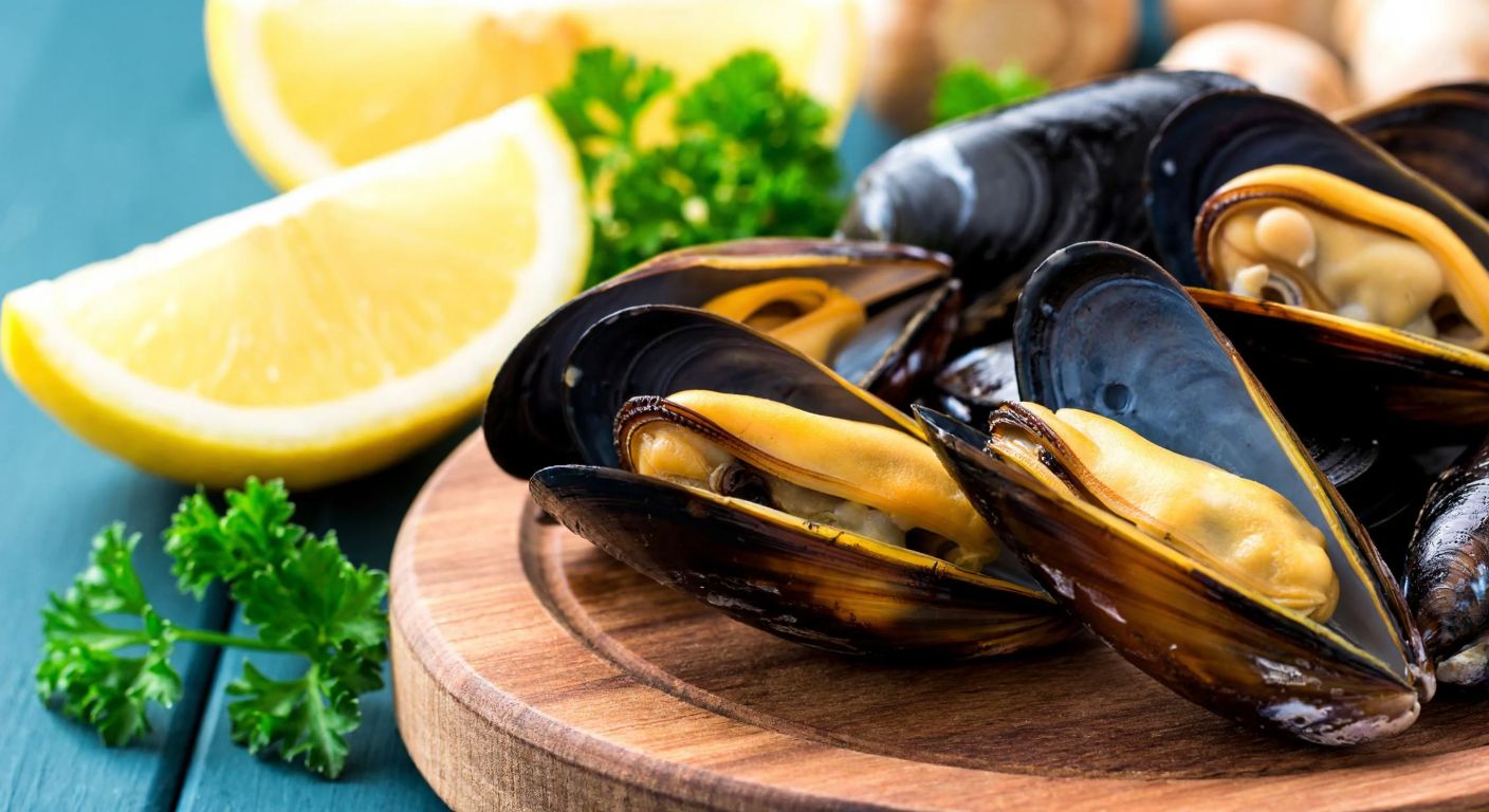 A close-up of fresh, glistening mussel meat on a rustic wooden plate, surrounded by lemon wedges and parsley, evoking the rich nutritional benefits of seafood in a Turkish coastal setting.
