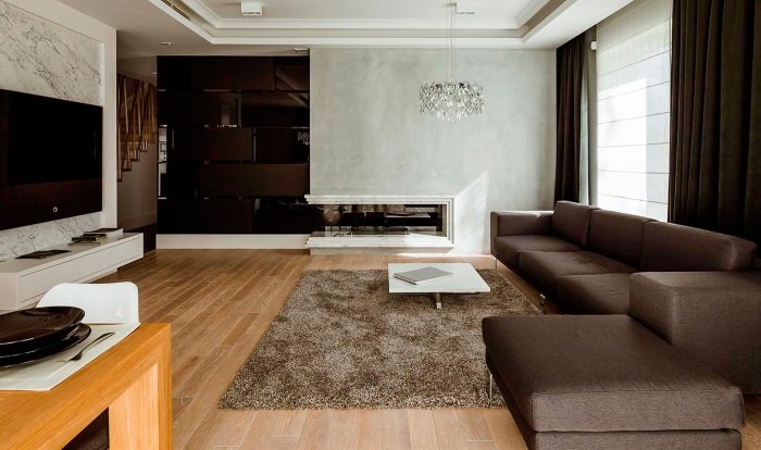 гостиная с коричневым прямым диваном и пуфом, светло-коричневым ковром, коричневым стеллажом и шторами