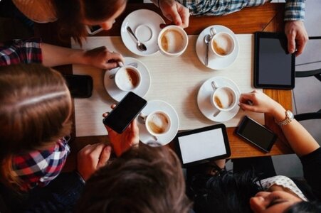 группа людей обсуждает книгу за столом с чашками кофе