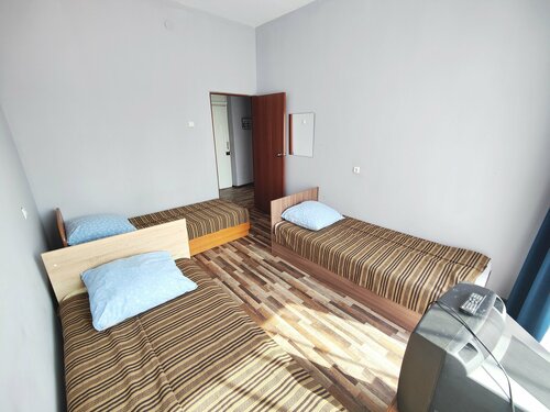 Односпальная кровать в общем номере для мужчин с общей ванной комнатой.