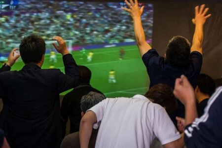 футбольные фанаты смотрят матч на большом экране