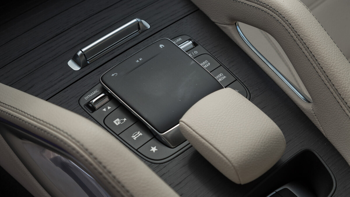 В Mercedes-Benz GLE управлять мультимедийкой можно как напрямую через экран, так и с помощью тачпада на центральной консоли. Рука идеально ложится на обитый кожей валик, но на ходу такое управление не слишком интуитивно: приходится «целиться» в пункты меню и постоянно отвлекаться от дороги, а тянуться к экрану далековато