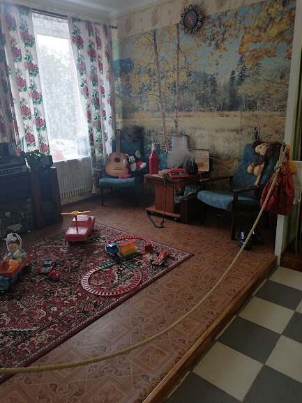 Ковер лежит на полу, а не висит на стене, как в середине XX в., на стене — модные в то время фотообои




