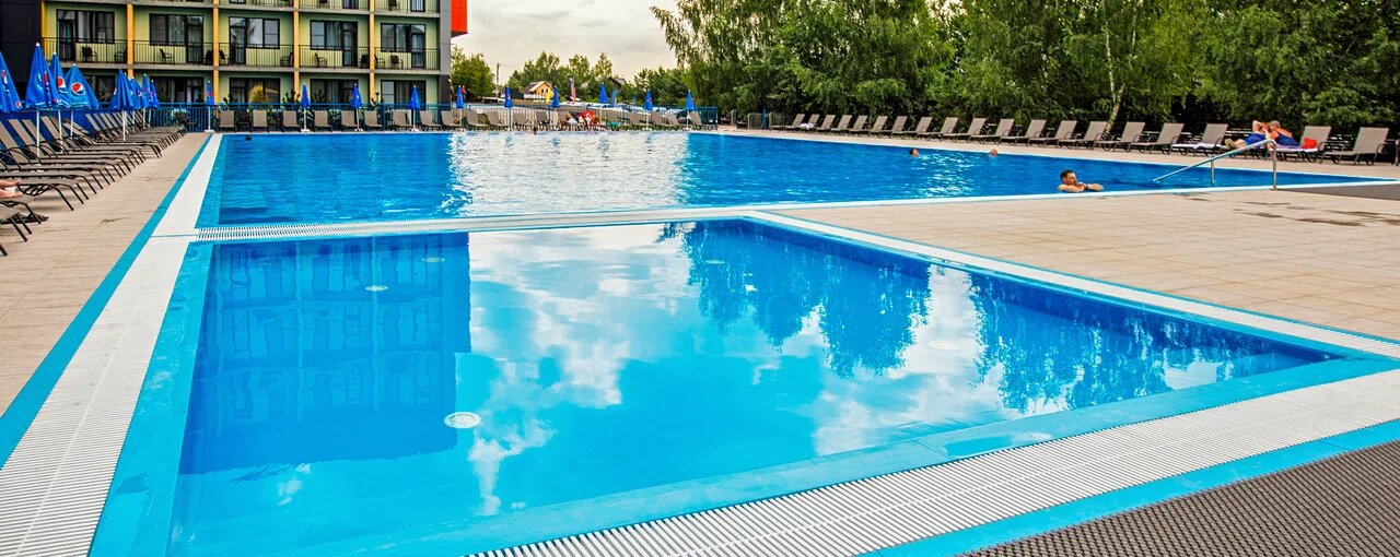 Вода в бассейне тёплая и прозрачная, дети плещутся рядом
