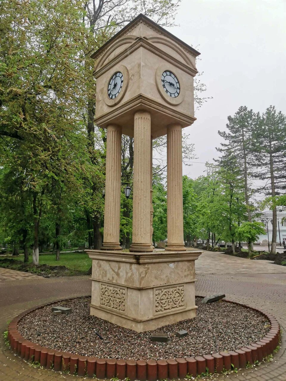 Между четырьмя колоннами стоит древняя амфора, а на вершине памятника установлены часы.