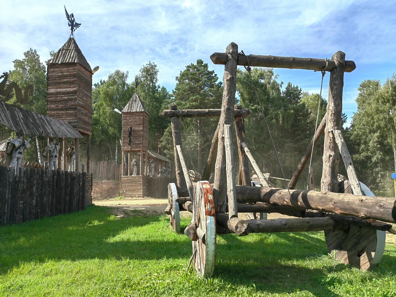 Около крепостной стены стоят макеты средневековых метательных орудий.