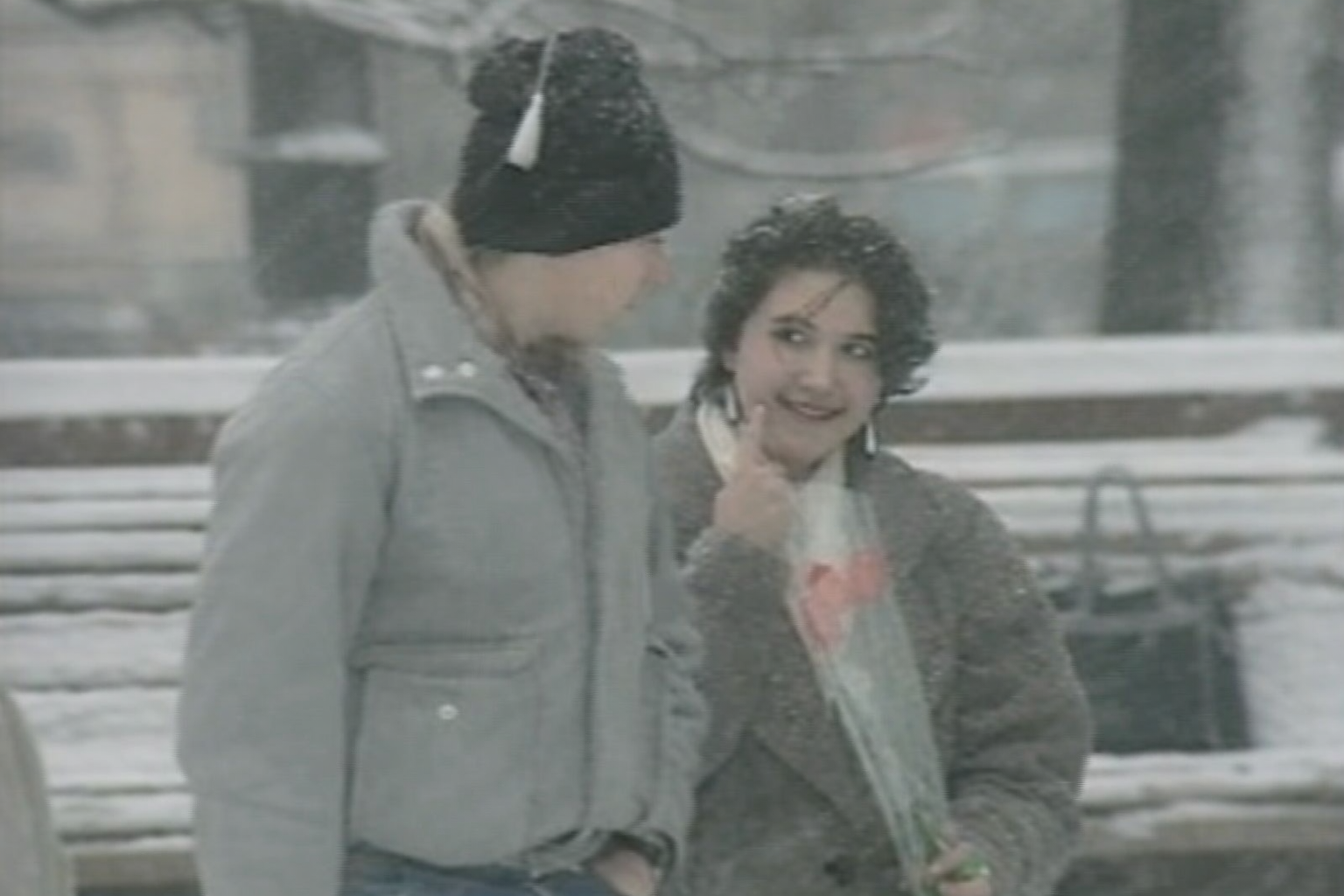 Тюльпаны к 8 Марта в 1990-е: мужчина дарит женщине букет на заснеженной улице — жест внимания, который становится главным символом праздника.