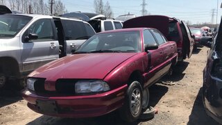 90s Oldsmobile Achieva at the junk yard