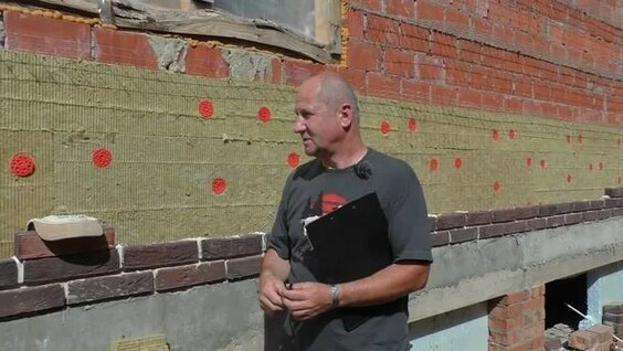 строитель показывает утеплитель на стройке