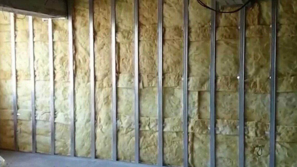 укладка минеральной ваты в обрешетку на стене дома