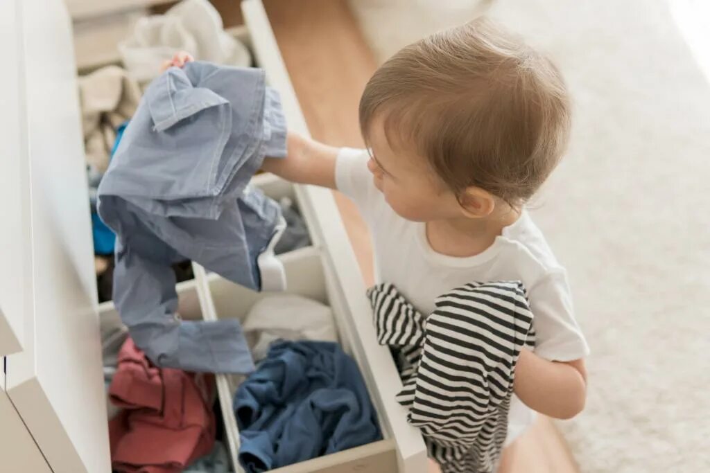 Детские вещи в дом ребенка. Ребенок одевается. Ребенок складывает одежду. Вещи для детей. Ребенок не хочет одеваться.