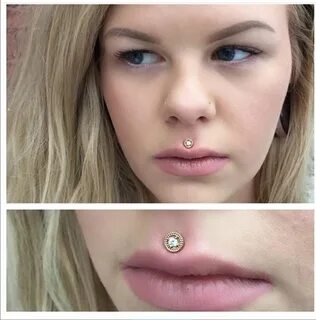 a woman with a nose piercing on top of her lip and bottom of her mouth.