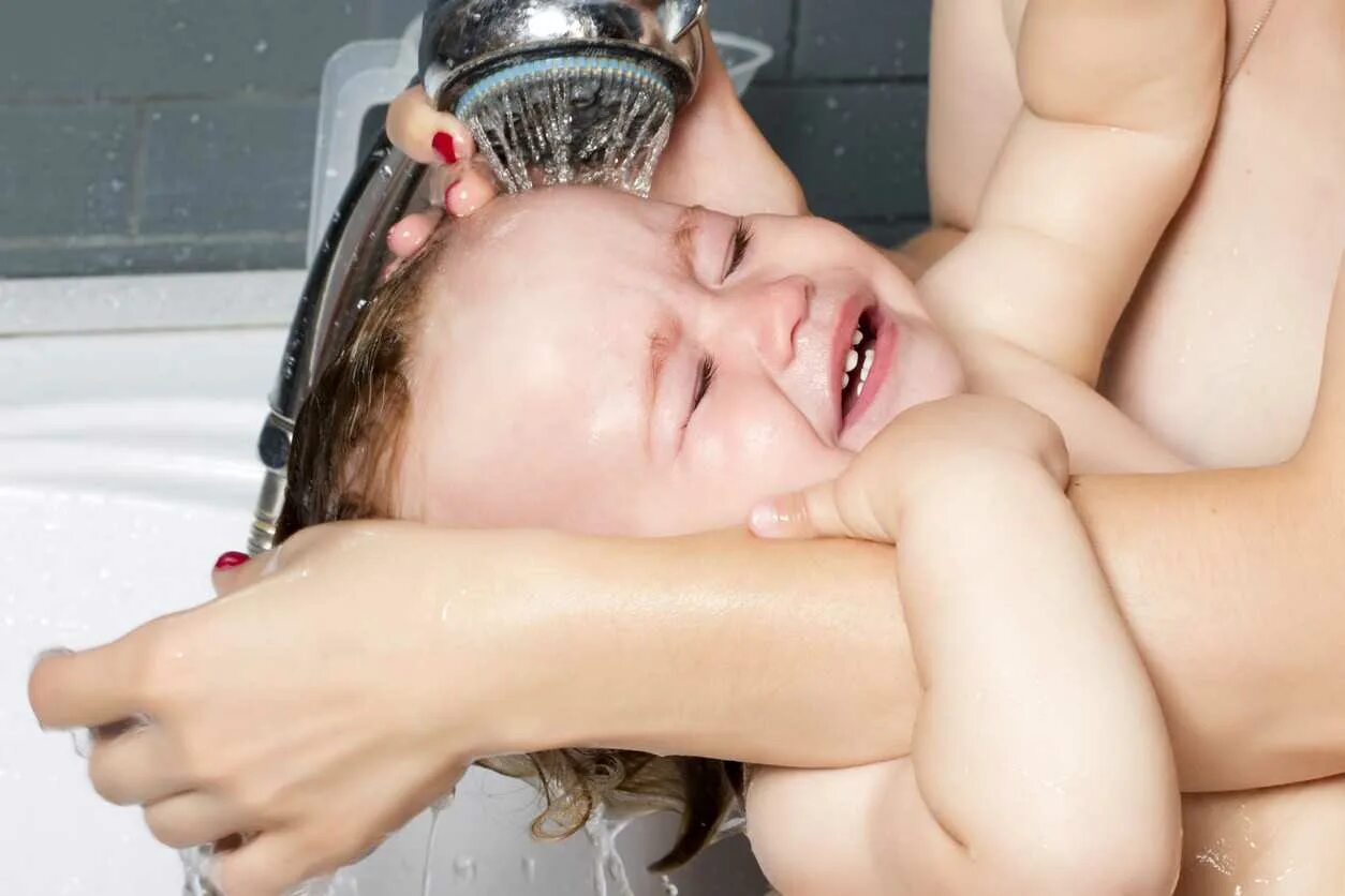 Мытье ребенка. Мытье головы. Ребенок плачет под душем. Мытье волос ребенка.