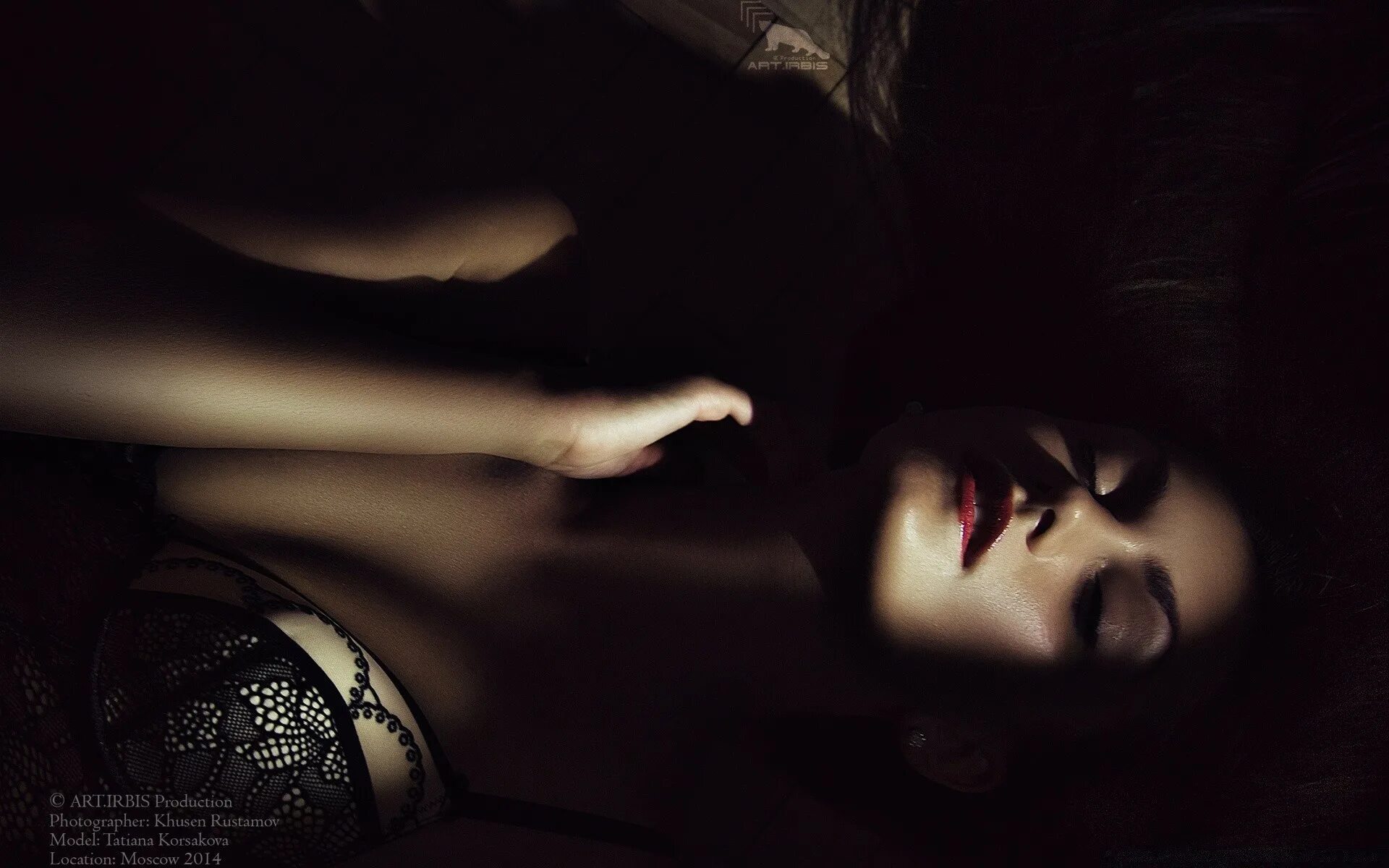 Девушка лежит в темноте. Девушка лежит на темном фоне. Женщина в полумраке. Красавица в темноте.