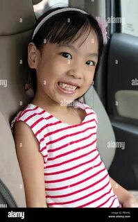 Happy Asian Little Chinese Girl sitting in the passenger seat inside of a c...