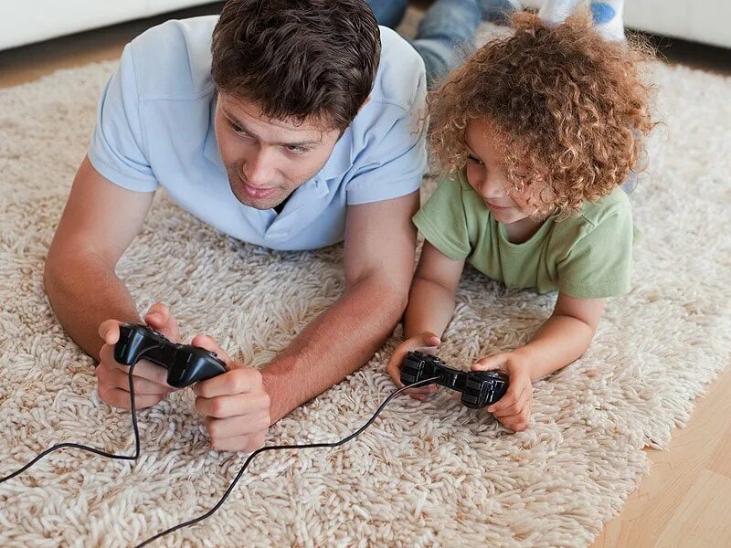 Отец и сын играют в Видеоигры. Папа и дети играют в видео игры. Мальчик лежит на ковре и играет в Видеоигры на своем смартфоне.. Папа играет в ванной.