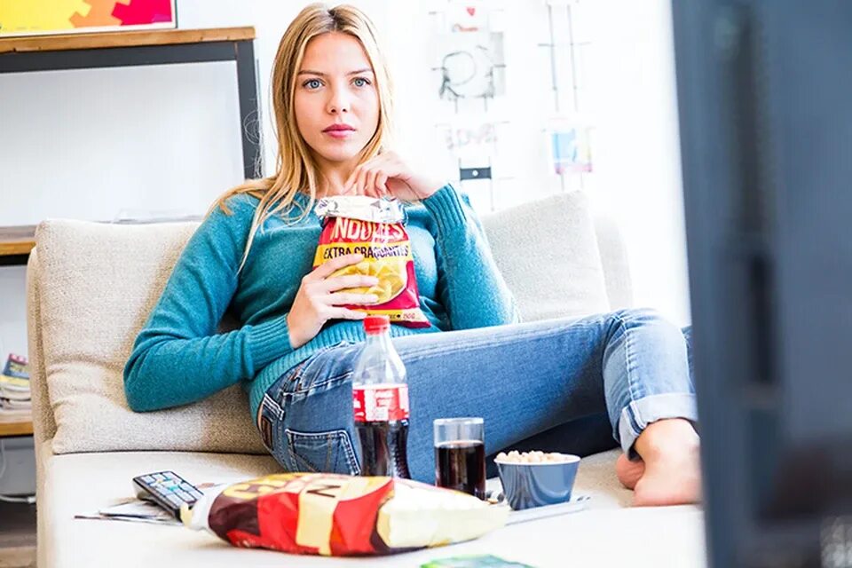 Девушка пообедаем. Eating while watching TV. Woman watching TV. Lady watch TV Computer. Unhealthy snack while working.