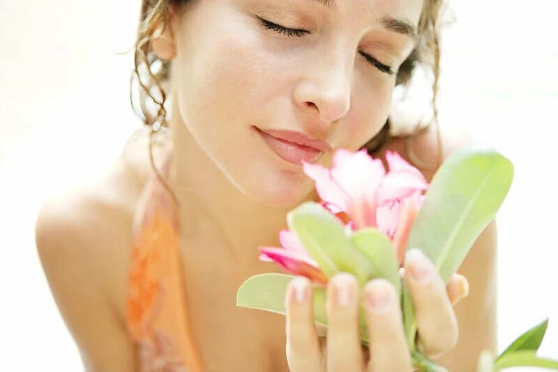 Масла для ароматерапии. Девушка в руках цветы нюхает. Охапка сена. Приятный запах. Девушка нюхает цветы.