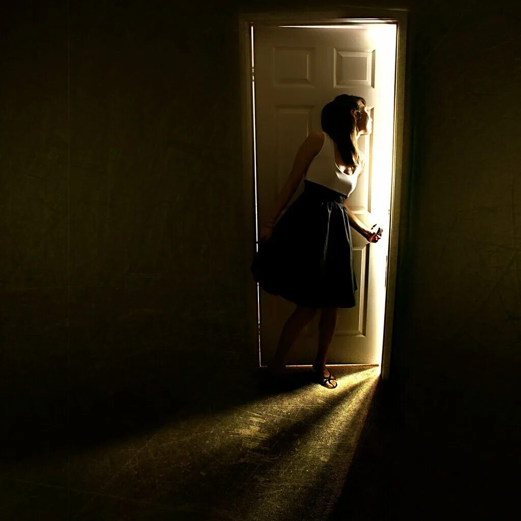 Открытая дверь. Девушка у двери. Девушка открывает дверь. Девушка в темной комнате. Смотрит через дверь