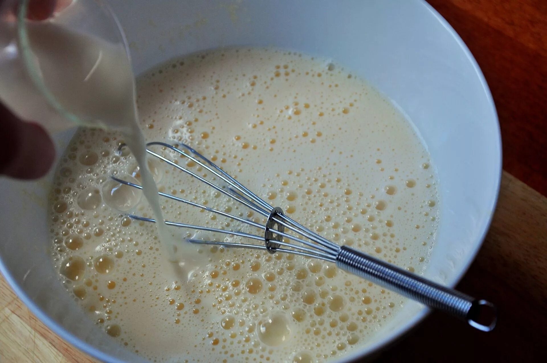 Замешивание блинов. Блинное тесто на молоке. Наливаем молоко в тесто. Смешать с молоком взбитые яйца. Блины на молоке нужно добавлять соду