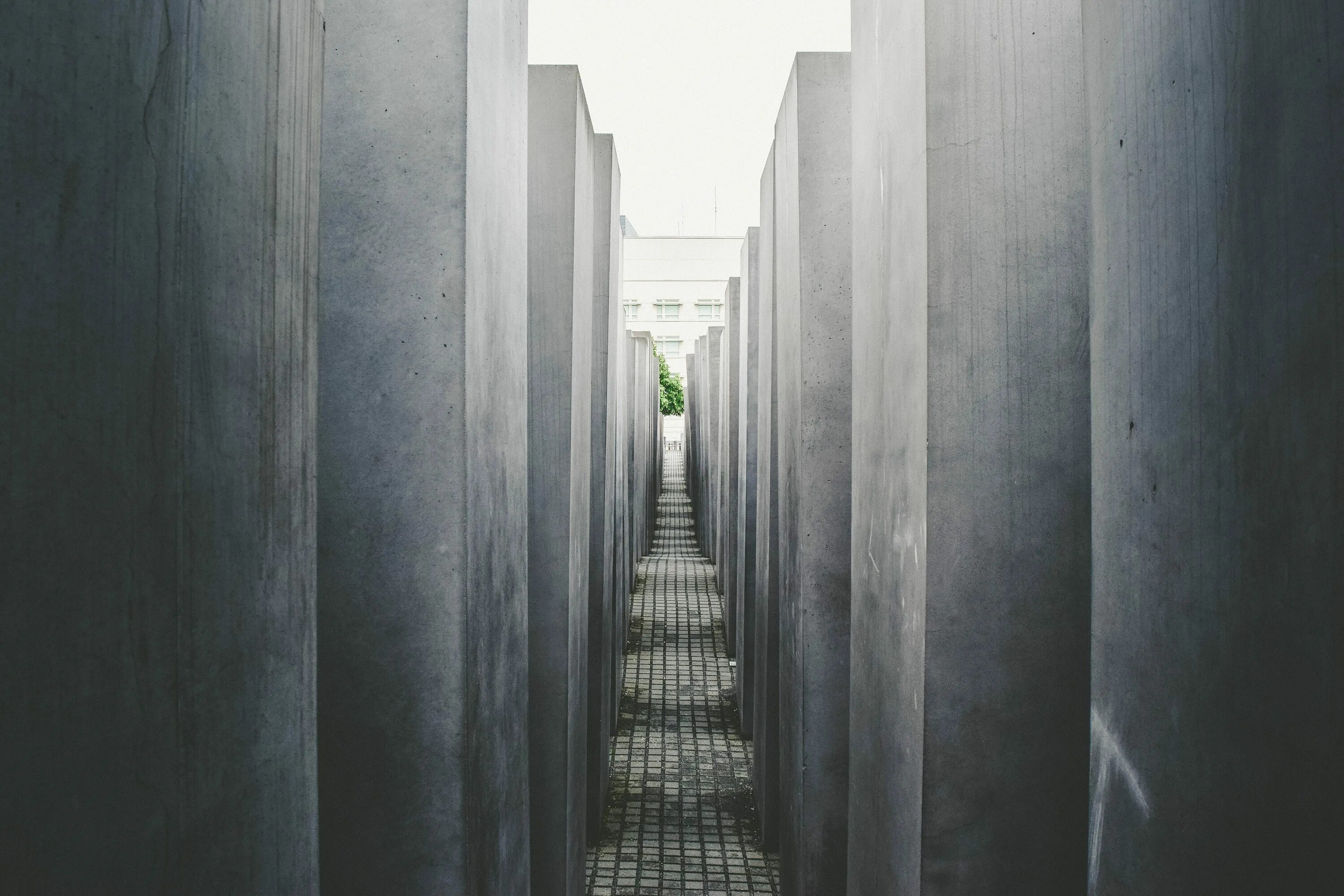 Стоит огромная стена. Мемориал жертвам Холокоста в Берлине. Бетонная стена. Стена в перспективе. Бетонный коридор.