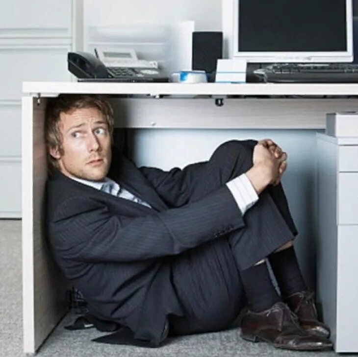Сбежать директору. Человек прячется. Офисный работник. Человек под столом офис. Человек прячется под столом.