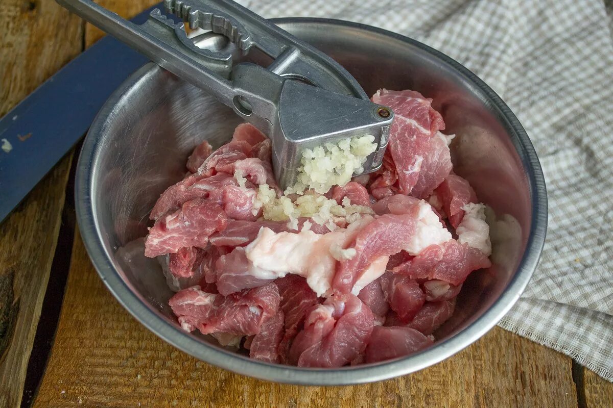 Термос для мяса. Чеснок под прессом на сковороде. Фото нарезанного мяса в миске.