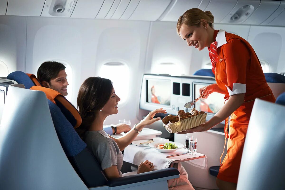 Самолете дают еду. Еда в самолете. Борт самолета. Пассажиры на борту самолета. Стюардесса с едой.