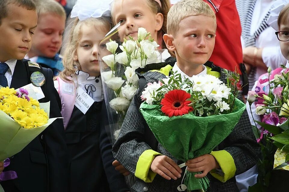 Первые дни в первом классе. Первое сентября. Школьники на линейке. Ученики на линейке. Дети на линейке в школе с цветами.