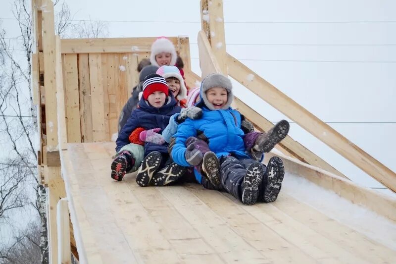 Ребенок катается с деревянной горки. Зимняя горка для детей. Дети катаются на Горке. Кататься с деревянной горки.