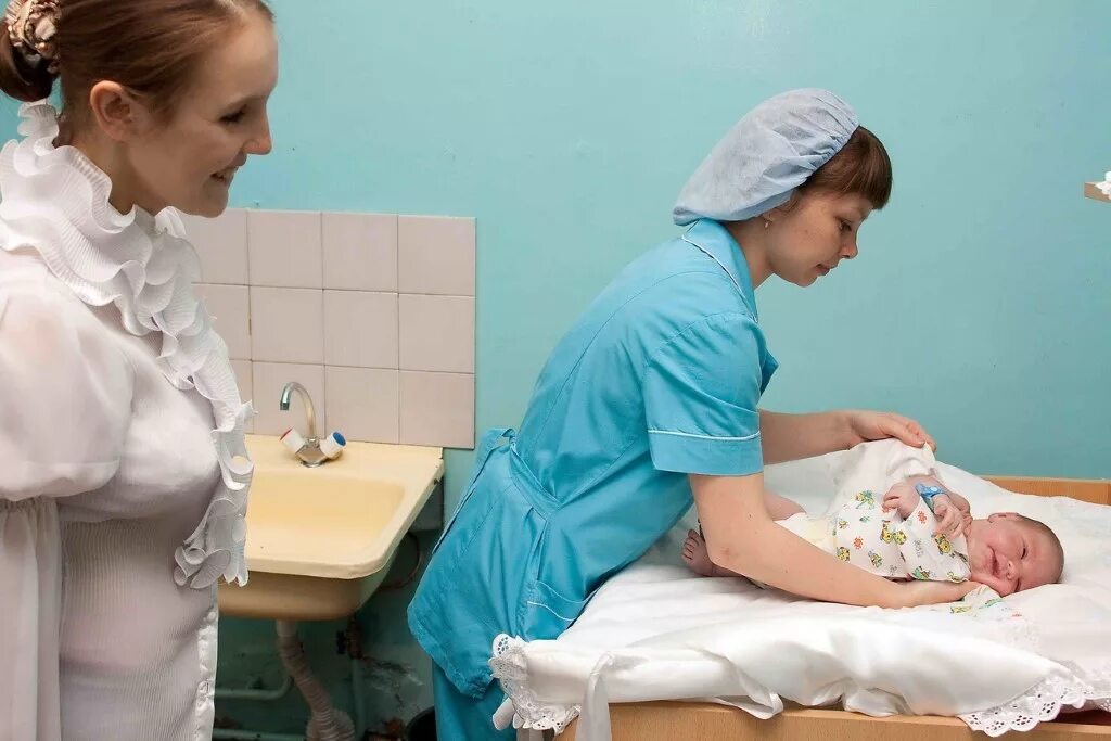 Акушерки принимающие роды. Медсестра в роддоме с новорожденным. Акушерка с новорожденным.