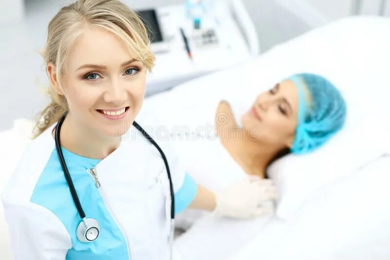 Медсестра лежит на кушетке. Врач слушает пациента. Женщина на кушетке в больнице. Молодая пациентка и молодой врач. Консультация гастроэнтеролога.