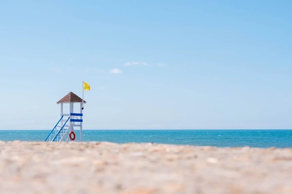Лето. Отдых на черном море. Спасательная вышка на пляже. Флаги на спасательной вышке на пляже.