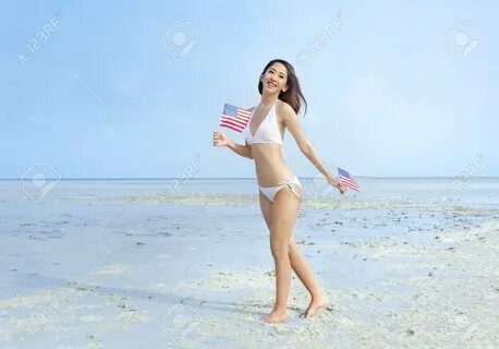 Asian girl in white bikini holding a little american flag on her hands on.....