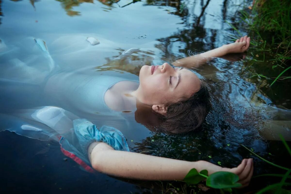 Девушка лежит в воде. Вода и человек. Девушка плавает.