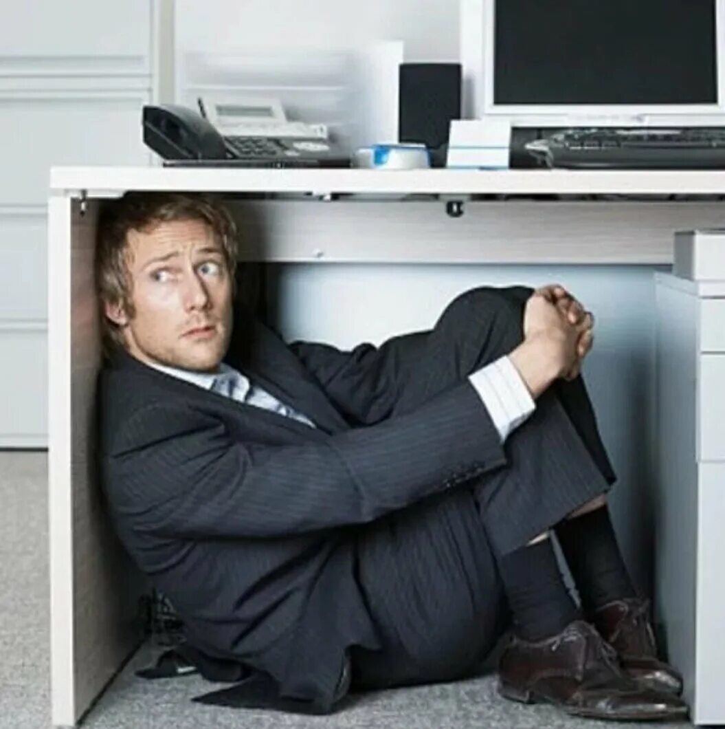 Невыносимо на работе. Человек прячется. Офисный работник. Человек под столом офис. Человек прячется под столом.