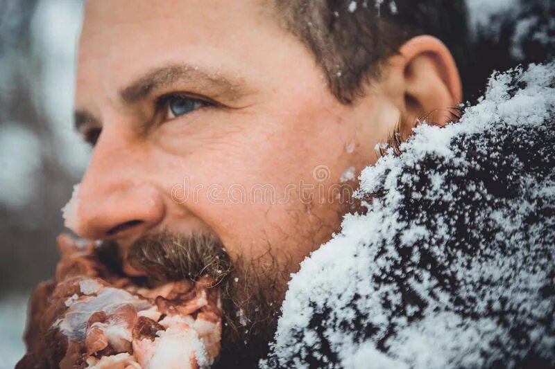 Снег голодный. Бородатый мужик ест мясо. Мужчина ест сырое мясо. Голодный человек с бородой.
