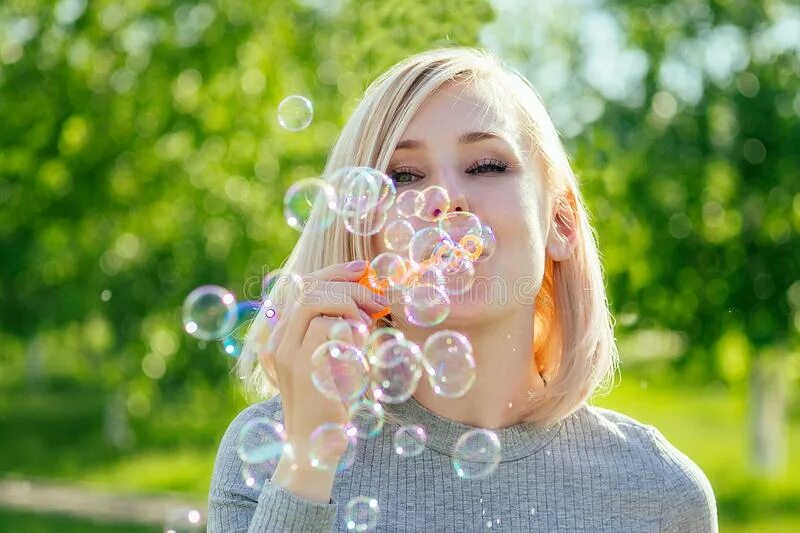 Блондинка с мыльными пузырями. Надувает мыльные пузыри. Девушка пускает мыльные пузыри. Блондинка дует на мыльные пузыри.