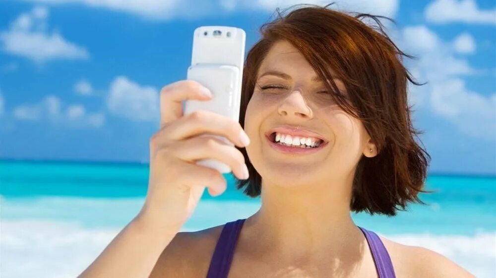 Звонки заграницу. Телефон на пляже. Роуминг за границей. Мобильная связь за границей. Говорить по смартфону на пляже.