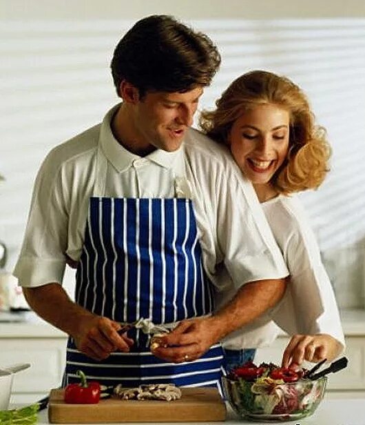 Пока жена готовит муж. Мужчина и женщина на кухне. Муж готовит на кухне. Мужчина в фартуке на кухне. Мужчина готовит для женщины.