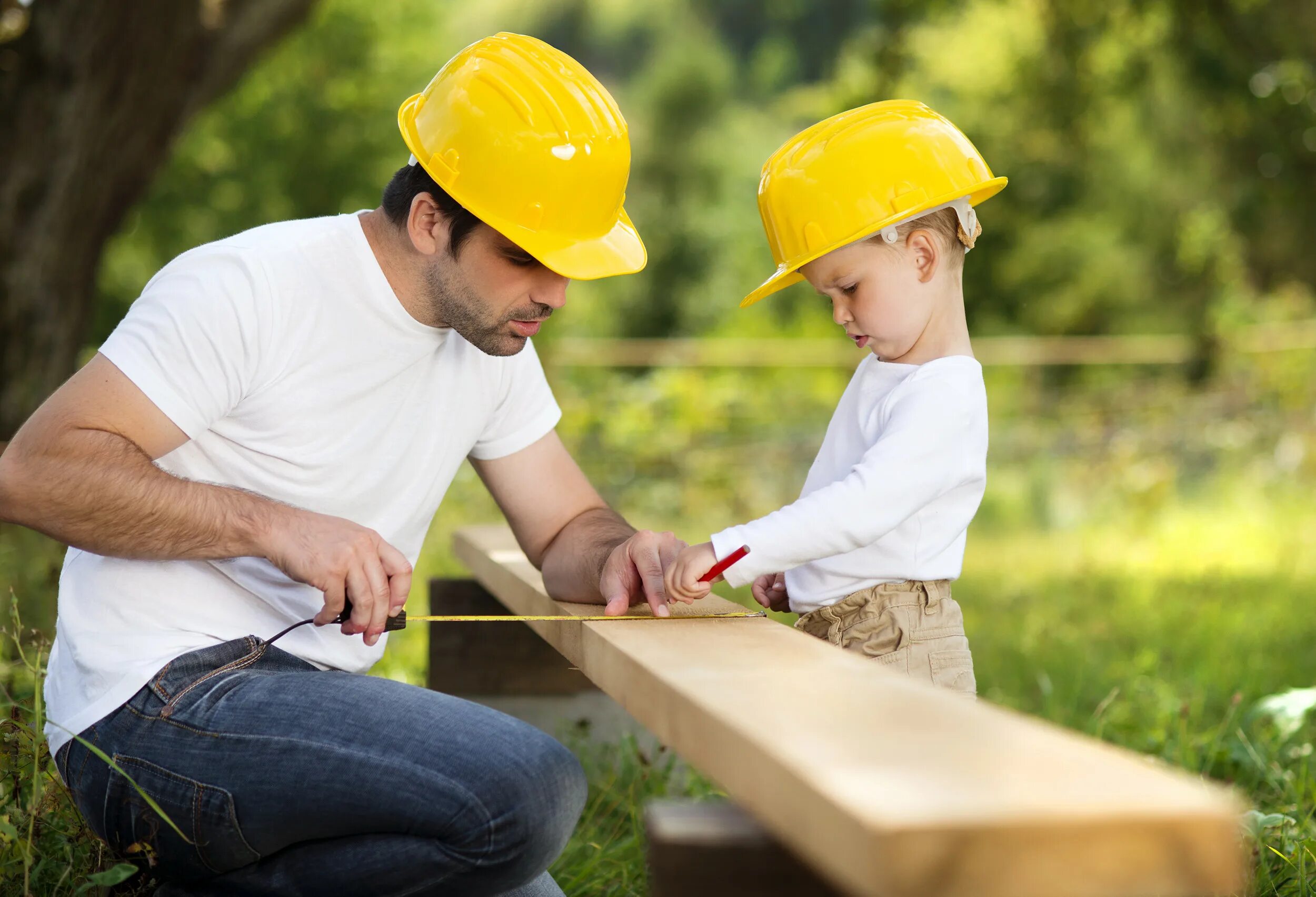 Мужчина строит дом. Ребенок в каске строителя. Стройка для детей. Человек трудится. Family tools