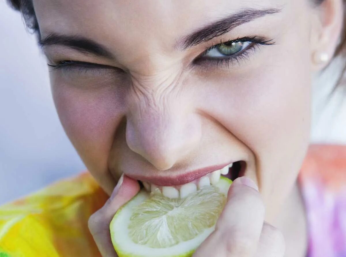 Металлическое ощущение во рту. Человек ест лимон. Кислый. Кислый вкус. Неприятный вкус во рту.