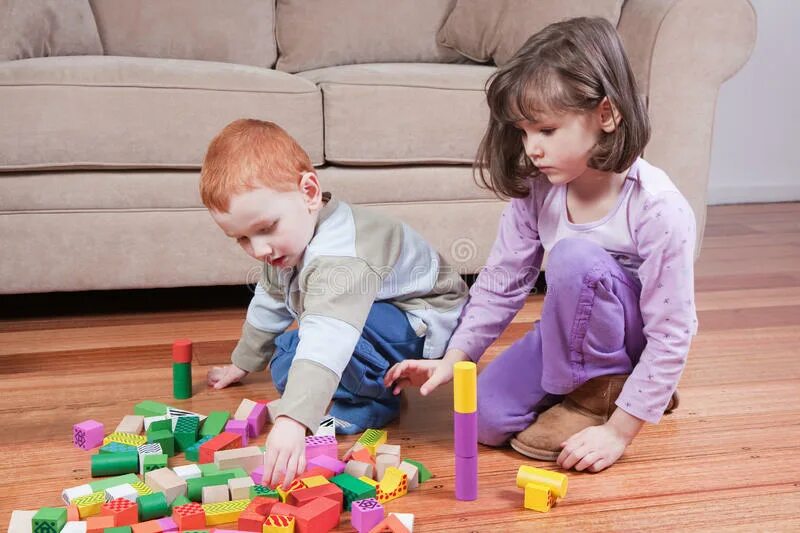 Дети играют на кровати. Родители играют с детьми в игрушки. Ребёнок играет за диваном. Картинка взрослый строит с ребёнком.