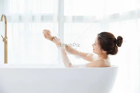Beautiful lady lying in the bathtub and taking a bubble bath. 